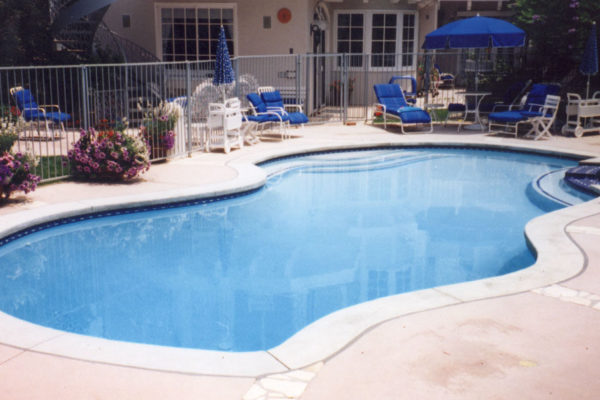 fenced-in-pool-with-lounge-chairs_riviera-pools-and-spas_premium-pool-builder-in-los-angeles-and-southern-california